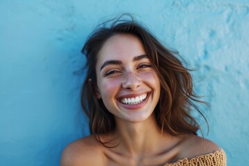 Portrait of a joyful young woman smiling against a blue background