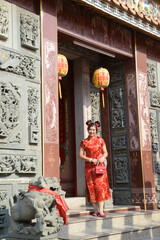 Portrait pretty Asian female in red traditional Chinese costume standing and posing in the shrine.