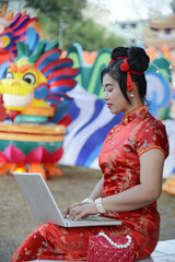 Pretty Asian woman working with laptop and a lantern puppet behind her.
