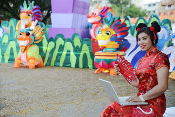 Pretty Asian woman working with laptop and a lantern puppet behind her.
