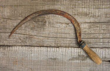 old rusty sickle on a wooden background. villager's tools.