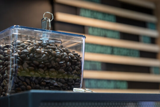 Close-up view of transparent plastic hopper with roasted coffee beans on black automatic bean-to-cup vending table top coffee machine. Soft focus. Copy space for your text. Hot drinks equipment theme.