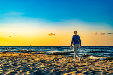 Beautiful mid adult woman walking on beach at sunset
