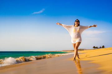 Fototapeta na wymiar Beautiful woman walking on sunny beach 
