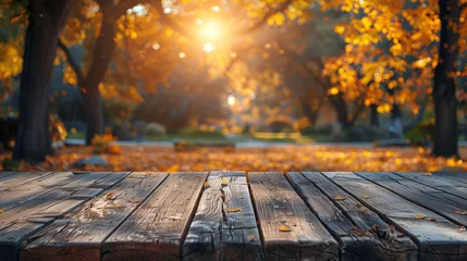 Deurstickers Wooden table top with autumnal park scene and warm sunlight in the background. © amixstudio