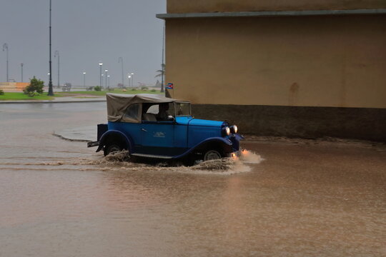 Old blue almendron car -Ford classic from 1931- drives down Marina Street wading a deep puddle in the heavy rain of a tropical storm. Havana-Cuba-123