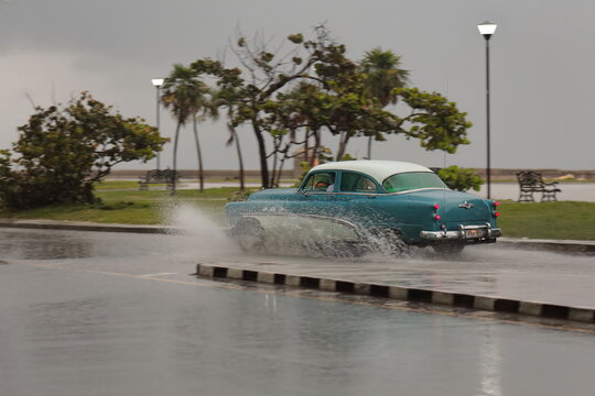 Old blue-white almendron car -Buick classic from 1953- drives down Jovellar and Marina Streets in the hard rain of a tropical storm. Havana-Cuba-126