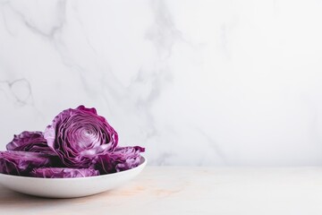 Purple cabbage in a white plate on a white marble background.