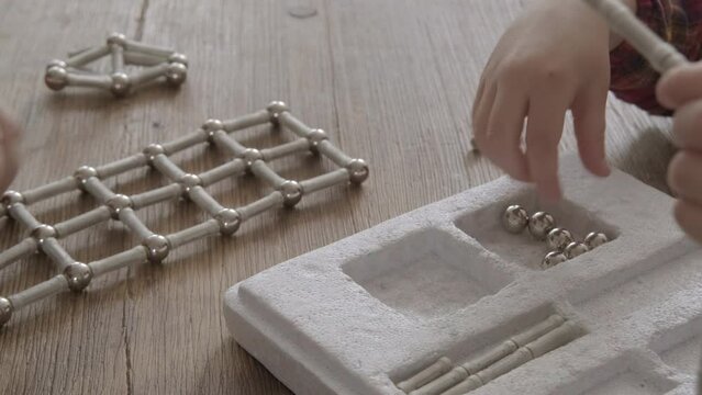 child, toddler assemble structures from magnetic constructor parts, development abstract, spatial thinking, child's imagination, engineering, fine motor skills