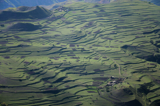 Inspiring Aerial Farming Landscape of Terraced Fields and Gardens on a Sunny day. Cultivation of land in villages high in the mountains. Shadows of Clouds fall on the Meadows Outside the city
