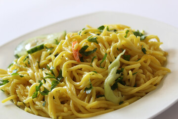 Bami Goreng, mie goreng, Indonesian fried noodles on a white plate. Close up shot. Selective focus shot.