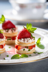 Mini strawberry and cream shortcake bites on a plate. Vertical, side view.