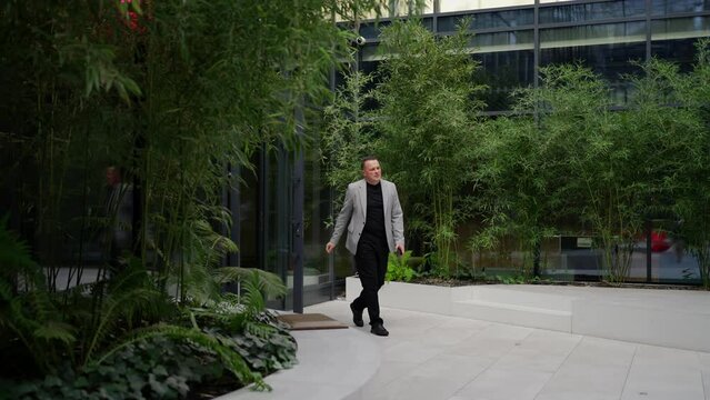 Dynamic Businessman Exiting Office to Lush Courtyard. A dynamic man exits the office door, stepping into a serene courtyard surrounded by bamboo.