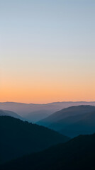 Layers of mountains receding into the distance under a smooth gradient evening sky