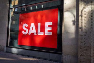 Eye-Catching Offer: Vibrant Red Sale Sign in a Storefront Window, Attracting Shoppers
