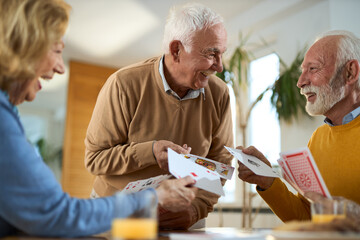 Group of happy seniors having fun while playing cards at home.	