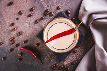 Close up of spicy coffee latte with chili pepper in a glass on the table top view