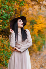 Young woman in fashionable attire showcasing fall fashion among the autumn trees