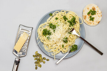Spaghetti with broccoli paste and fork and spoon on ceramic plate.