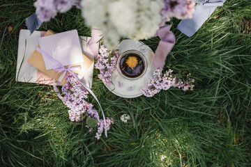 Serving on a green lawn: a lilac in a vase, a floral Chinese natural tea brewed in a glass cup, a...