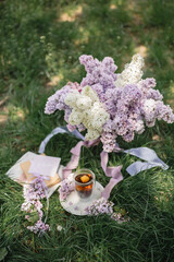 Serving on a green lawn: a lilac in a vase, a floral Chinese natural tea brewed in a glass cup, a...
