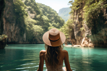 Woman in a straw hat admiring the serene emerald waters surrounded by cliffs.