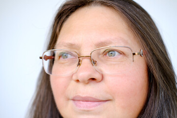 close-up female face of elderly woman 50 years old with long hair in glasses, on lips slight smile...