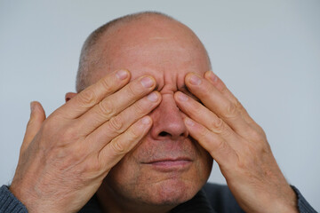 close-up part of mature male face, man 60-65 years old closed tired eyes with her fingers, vision...