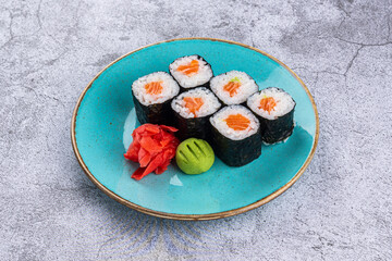Maki sushi rolls with salmon in a plate on a gray background