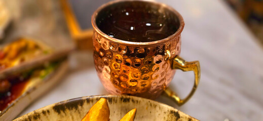 Traditional iced tea served in a unique and artistic brass cup , ice tea garnished with rosemary...
