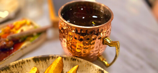 Traditional iced tea served in a unique and artistic brass cup , ice tea garnished with rosemary...