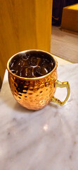 Traditional iced tea served in a unique and artistic brass cup , ice tea garnished with rosemary...
