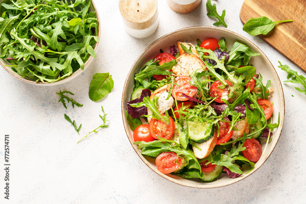 Sticker green salad with baked chicken breast, fresh salad leaves and vegetables.