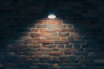 Single flood light partially illuminates rustic brick wall