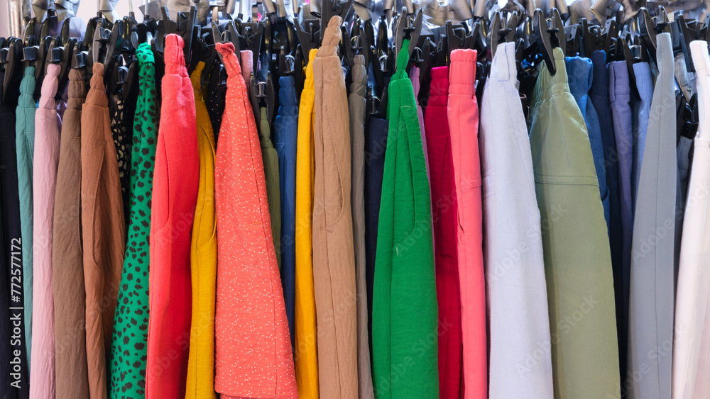 Aufkleber A rack of clothes with a variety of colors and patterns. The clothes are hanging on hangers and are organized by color. Concept of abundance and variety