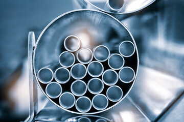 A bunch of metal tubes are stacked in a circle. The tubes are silver and appear to be of varying...