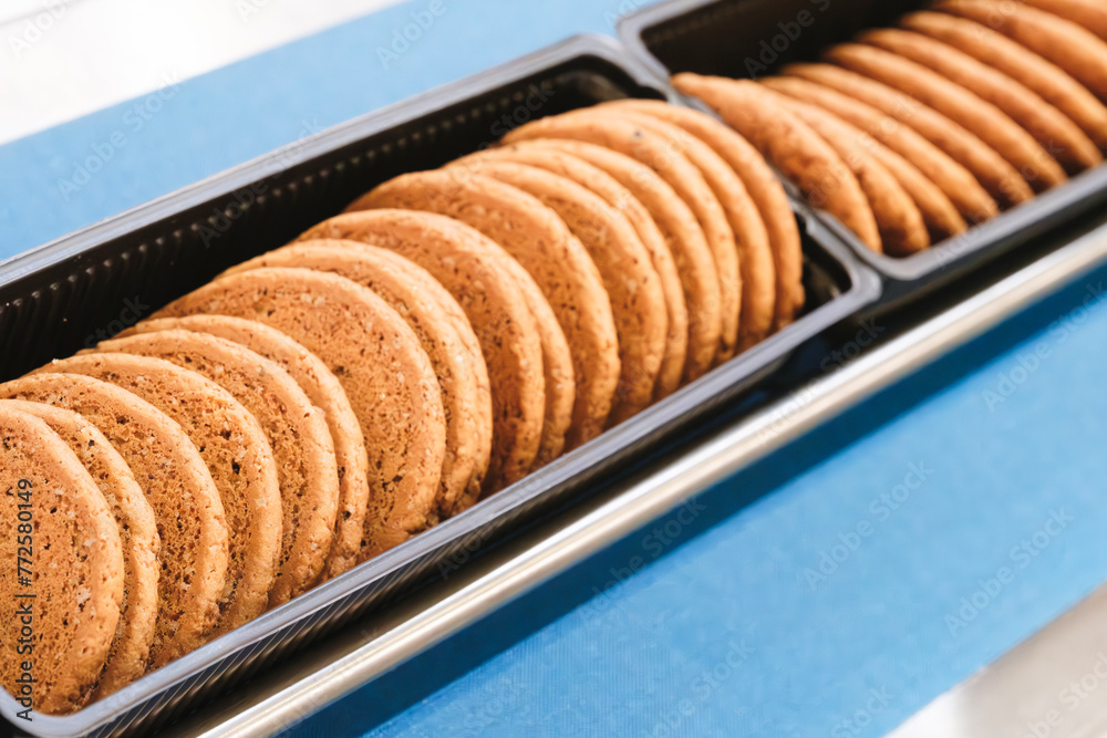 Poster A tray of cookies is sitting on a counter. The cookies are all the same size and are arranged in a row