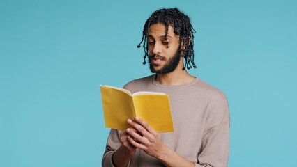 Middle Eastern man reading book from publisher aloud, telling story, enjoying hobby. BIPOC person...