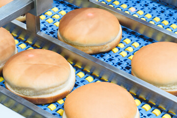 Conveyor belt next to a hamburger bun. All buns are divided into halves of the same size and shape...