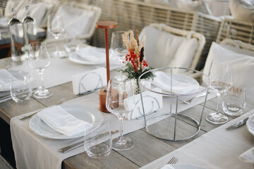 Beautifully organized event - round served table banquet ready for guests, round decorated table with empty plate, glasses, forks, napkin. Elegant dinner table 
