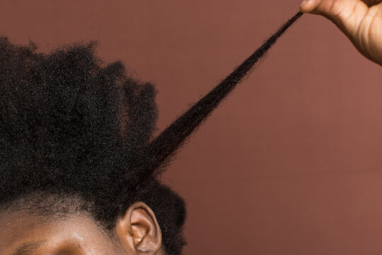 A woman stretching her curly hair to emphasize shrinkage, 4c hair stretched to show shrinkage