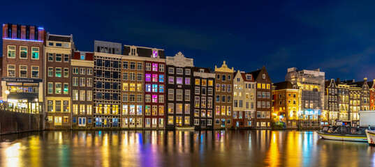 Night time shot of the Singel canal, Amsterdam with historic buildings along the bank and light flare - obrazy, fototapety, plakaty