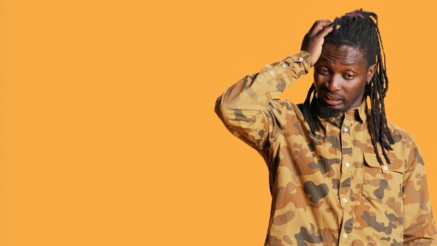 Pensive african american guy is confused and sceptic, contemplating about something in studio. Young man being uncertain and clueless about answer, reflective focused adult. Handheld shot.