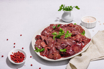Raw chicken liver on stone background. Fresh ingredients ready for cooking, parsley, red pepper