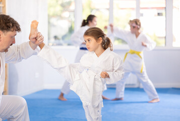Father and daughter karatekas in kimonos practice karate fighting in studio