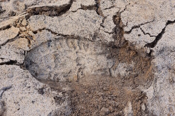 shoe sole print on the gray brown sand of the road in the street