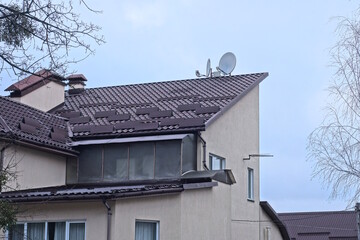 part of the roof of a private house under a tiled roof with a windows against the gray sky