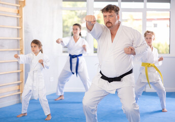 Children with parents in kimono standing in fight stance during group karate training