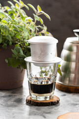 Vietnamese phin on a glass, Vietnamese coffee with condensed milk, herbs in a pot and kettle - 772591307