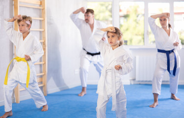 Family of karatekas with two children practicing karate techniques in gym